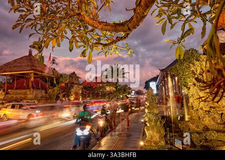 Viel Verkehr auf der Jalan Raya Ubud Straße in der Abenddämmerung. Ubud, Bali, Indonesien. Stockfoto