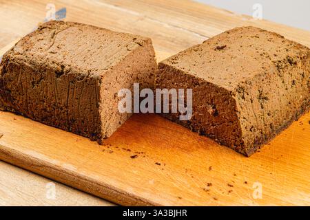 Frisch zubereitete Hühnerleberpastete, perfekt geschnitten und auf einem Holzschneidebrett präsentiert. Dieses Gericht hat eine glatte Textur und satte Farbe, ideal Stockfoto