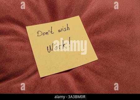 Eine hellgelbe Haftnotiz mit handgeschriebenem Text auf einem weichen, rotbraunen Kissen. Die Notiz vermittelt eine motivierende Botschaft über die Fokussierung auf W Stockfoto