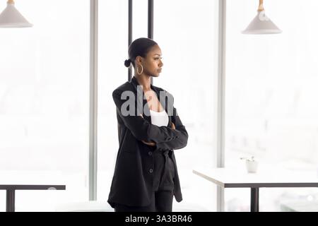 Junge nachdenkliche afrikanische Geschäftsfrau, die allein im Coworking Space steht Stockfoto