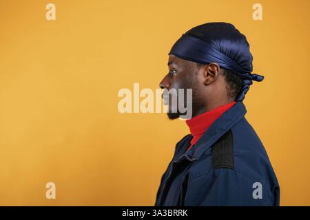 Blick von der Seite. Ein hübscher schwarzer Mann ist im Studio vor gelbem Hintergrund. Stockfoto