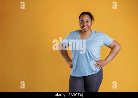 Stehen und posieren. Afroamerikanerin ist im Studio vor gelbem Hintergrund. Stockfoto
