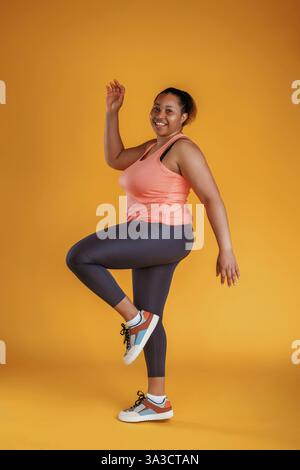 Fitness machen. Afroamerikanerin ist im Studio vor gelbem Hintergrund. Stockfoto