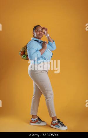 Kunde mit einem Haufen Obst in der Tasche. Afroamerikanerin ist im Studio. Stockfoto