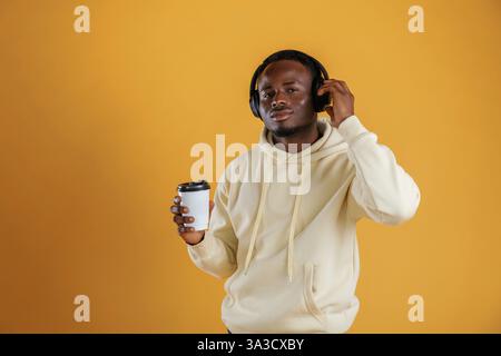 Kaffee und Kopfhörer. Der Schwarze ist auf gelbem Hintergrund. Stockfoto