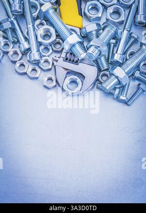Vertikale Ansicht der verstellbaren Schlüsselbolzen aus Metall und Schraubenmuttern auf einem Konstruktionskonzept mit Metallhintergrund Stockfoto