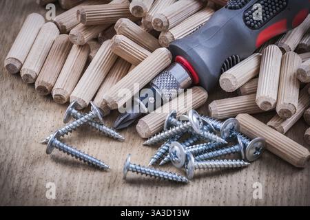Holzdübel Edelstahlkonstruktionsnägel isolierter Schraubendreher auf Holzplatte Stockfoto