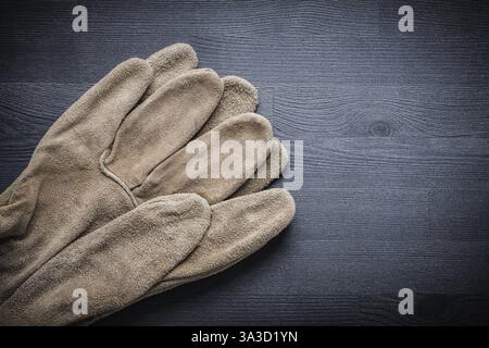 Zwei Schutzhandschuhe auf dunklem Holzbrett Stockfoto
