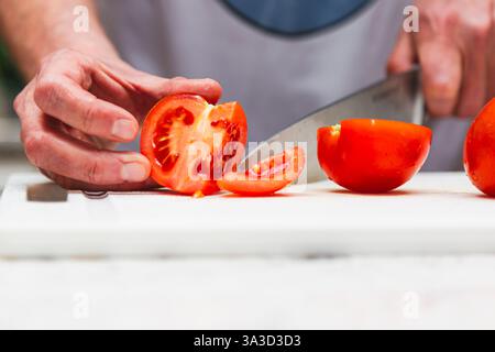 Hände eines Kochs, der frische Tomaten schneidet Stockfoto