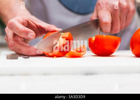 Hände eines Kochs, der frische Tomaten schneidet Stockfoto