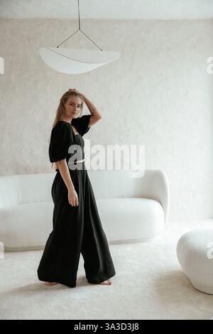 Schöne junge Frau in schwarzem Kleid ist drinnen und posiert. Stockfoto
