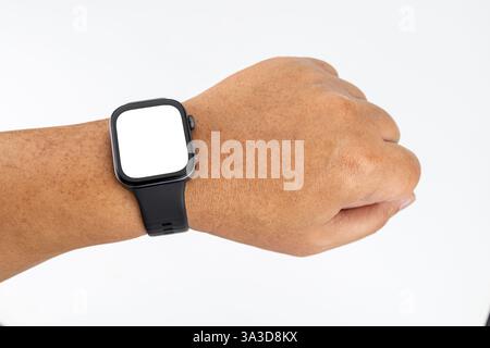 Ein molliger asiatischer Mann mit gelber Haut, der eine schwarze Smartwatch am Handgelenk mit einem weißen Bildschirm trägt. Stockfoto