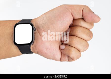 Ein molliger asiatischer Mann mit gelber Haut, der eine schwarze Smartwatch am Handgelenk trägt, mit einem weißen Bildschirm. Stockfoto