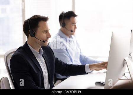 Beschäftigter Contact-Center-Manager in Lateinamerika im Headset, der auf den Monitor zeigt Stockfoto