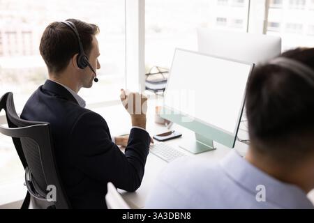 Verschiedene Client-Support-Manager in Headsets, die am Monitor arbeiten Stockfoto