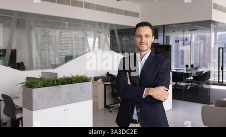 Glücklicher hispanischer Geschäftsführer, der in einem modernen, stilvollen Büro steht Stockfoto
