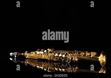 Jazz. Ein Saxophon auf Spiegelfläche vor schwarzem Hintergrund, Platz für Text Stockfoto