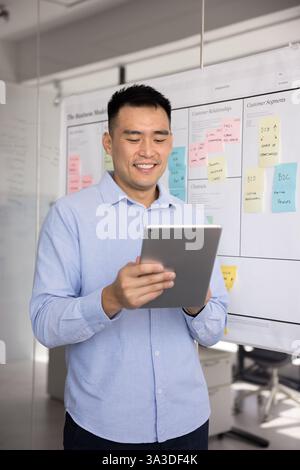 Fröhlicher asiatischer Projektmanager, der den Internet-Marketing-Bericht analysiert Stockfoto