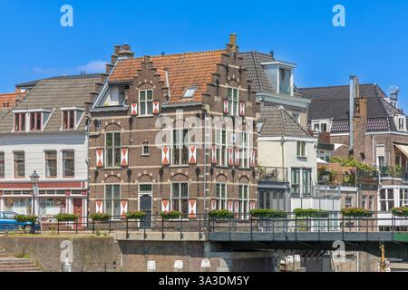Gorinchem, Niederlande. 25. Juni 2024. Typische Häuser mit rot-weißen Fensterläden am Fenster in der befestigten Stadt Gorinchem entlang der Brücke an Stockfoto
