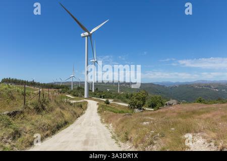 Mehrere große moderne Windmühlen in den Bergen mit einsamen Straßen und blauem Himmel in der Fafe-Region Portugals Stockfoto