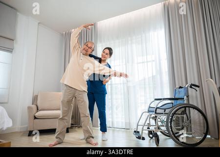 Der alte Senior-Mann trainiert zu Hause gern mit einem Physiotherapeuten für ausgestreckte Arme Stockfoto