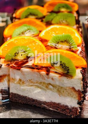Lebendiger Kuchen mit Fruchtgarnitur mit Kiwi- und Orangenscheiben - erfrischendes Dessert mit cremiger Füllung - perfekt für Partys und Feiern - Gourmet-Gebäck mit frischen, saftigen Früchten Stockfoto
