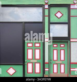 Grüne und rote Schaufensterfront mit symmetrischen Doppeltüren mit geometrischen dekorativen Elementen, die eine markante architektonische Komposition schaffen.r Stockfoto