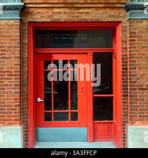 Roter, Vintage-Eingang mit Glasscheiben vor einer reichen Backsteinfassade, die historische Architektur Chicagos zeigt Stockfoto