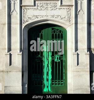 Eine grüne Metalltür markiert den Eingang zu einem Grab, eingerahmt von detaillierten Mauerwerken. Stockfoto