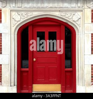 Roter Bogengang im gotischen Stil, eingerahmt von komplizierten Steinschnitzereien in einem historischen Backsteingebäude. Stockfoto