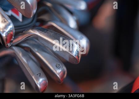 Nahaufnahme verschiedener nummerierter Eisengolfschläger in einer Golftasche mit Schwerpunkt auf den polierten Schlägerköpfen aus Metall Stockfoto