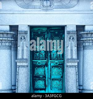 Blaugrüne Metalltür des ägyptischen Revival-Grabes mit komplizierten Blumen- und geometrischen Motiven, flankiert von detaillierten Säulen und von Hieroglyphen inspirierten Schnitzereien Stockfoto