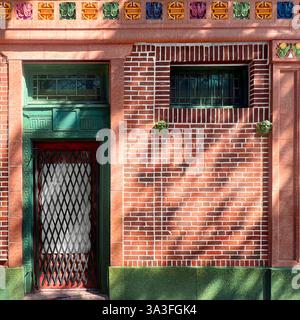 Grüne Tür, umgeben von komplexen architektonischen Details, farbenfrohen Terrakotta-Akzenten und rosafarbener Ziegelfassade in Chicagos Chinatown. Stockfoto