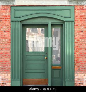 Elegante grüne Holztür mit Glaspaneelen, Messingbeschlägen und einem bogenförmigen dekorativen Rahmen in einer rosafarbenen Ziegelfassade in Chicago. Stockfoto