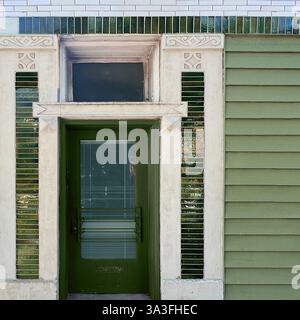 Eine grüne Tür mit dekorativen verglasten Backsteinen und komplexen architektonischen Details an einer alten Fassade des Chicagoer Gebäudes. Stockfoto