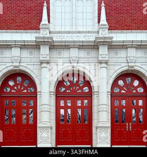 Neoklassizistischer Eingang der Versammlungshalle mit leuchtenden roten Türen, verzierten weißen Steindetails und großen Bogenfenstern in Chicago Stockfoto