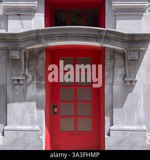 Rote Tür mit Glaspaneelen in einer kunstvollen Steinfassade, die historische und moderne architektonische Elemente Chicagos verbindet Stockfoto