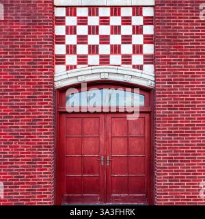 Ein historischer Eingang aus rotem Backstein mit doppelten Holztüren und einem kunstvollen Schachbrettstein in Chicago Stockfoto