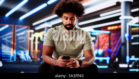 Personal Trainer unterstützt Frau bei der Nutzung der Fitness-App auf dem Smartphone Stockfoto