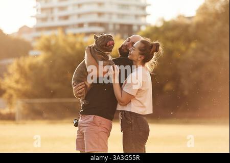 Das Tier in der Hand halten. Mann und Frau sind mit Hund auf dem Feld. Stockfoto