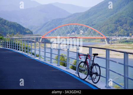 Gurye County, Südkorea - 3. Oktober 2021: Ein Rennrad lehnt sich an das Geländer des Seomjingang Bike Path, mit der Namdo Bridge über das Seom Stockfoto