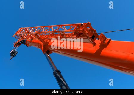 Baukranarm mit Haken vor blauem Himmel. Mobiler Turmkran mit Teleskopausleger Stockfoto