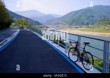 Gurye County, Südkorea - 3. Oktober 2021: Ein Rennrad ruht entlang des Seomjingang Bike Path mit Blick auf den Seomjin River und die Namdo Bridge Stockfoto