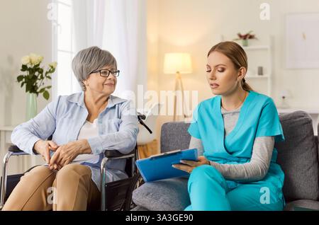Freundliche Krankenschwester, Arzt gibt Hilfe, Unterstützung für behinderte alte Patientin, die im Rollstuhl sitzt Stockfoto
