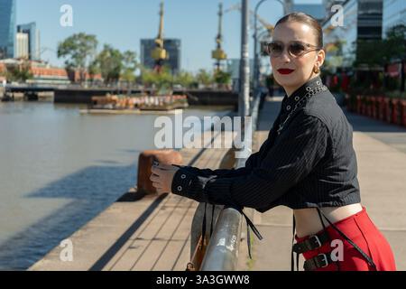 Influencerin posiert am Fluss in buenos aires, zeigt ihr Outfit und genießt den sonnigen Tag Stockfoto