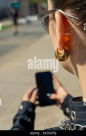 Nahaufnahme einer Frau, die mit Smartphone eine Skateboarderin aufnimmt, die im urbanen Skatepark praktiziert Stockfoto
