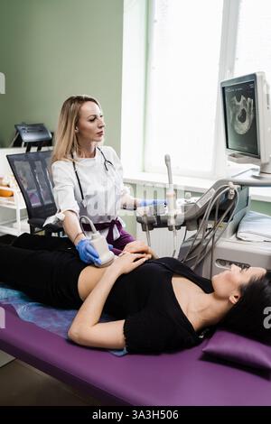 Gynäkologe führt Ultraschalluntersuchungen für schwangere junge Frau in der frühen Schwangerschaftsperiode und schauen auf den Bildschirm im Krankenhaus. Schwangerschaft und Mutterschaft Stockfoto