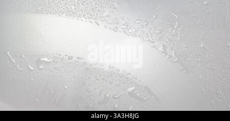 Wischen Sie die Glasscheibe mit einem Glasreiniger und einem Gummiabzieher ab. Hygiene, Wassertropfen oder Spritzer, Flecken Desinfektion auf einer klaren Oberfläche. Stockfoto