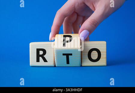 RPO vs. RTO-Symbol. Geschäftsmann-Hand dreht Holzwürfel und ändert das Wort RTO in RPO. Wunderschöner blauer Hintergrund. Geschäftskonzept. Kopierbereich Stockfoto