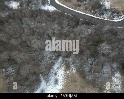 Blick aus der Vogelperspektive auf den Winterwald mit gewundenen Fluss und schneebedecktem Boden Stockfoto